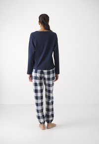 Marinblå långärmad topp med en avslappnad passform, tillsammans med rutiga pyjamasbyxor i marinblått och vitt, med elastiska mudd och en mjuk textur.