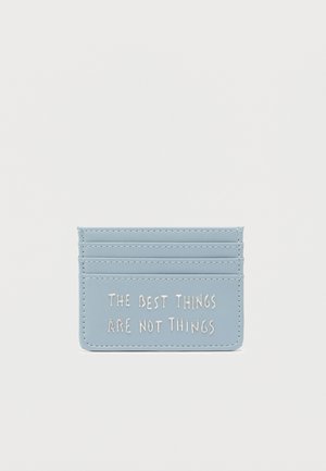 Šviesiai mėlynas dirbtinės odos kortelių laikiklis su penkiomis kišenėlėmis. Balti reljefiniai užrašai: „GERIAUSI DALYKAI YRA NE DAIGAI.“ Lygus paviršius, minimalistinis dizainas.