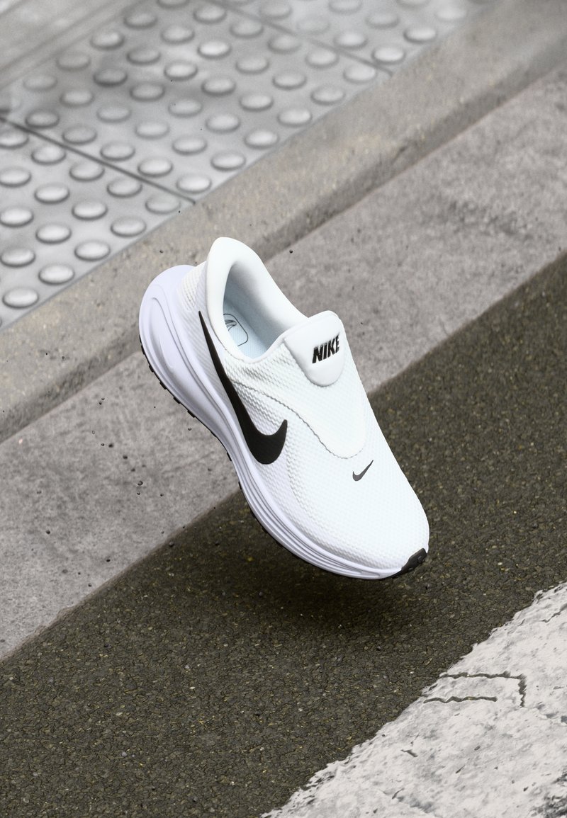 Baskets blanches Nike avec empeigne en mesh texturé, logo Swoosh noir et bout arrondi. Conception légère avec une semelle coussinée.