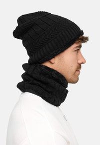 Black knit beanie and matching neck warmer, both featuring ribbed and textured patterns. Soft, warm fabric, shown from the side.