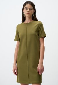 Olivgrünes Kurzarmkleid mit rundem Ausschnitt, das eine Mittelnaht und eine glatte, strukturierte Textur aufweist. Keine sichtbaren Verschlüsse.