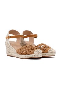 Sandalias de cuña con parte superior de ganchillo marrón, tiras beige en el tobillo y una media suela de yute trenzado. Presenta recortes florales y una punta redondeada.