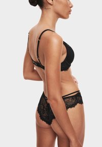 Czarny zestaw bielizny składający się z koronkowego biustonosza z regulowanymi ramiączkami oraz pasujących koronkowych majtek z misternymi wzorami i detalami wykończenia.