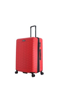 Red hard-shell suitcase with a honeycomb texture, black zipper and handle, dual wheels, and side carry handle. Brand logo displayed prominently.