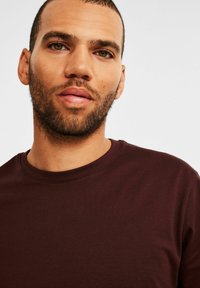 Bordeaux crew-neck T-shirt van katoen, korte mouwen, gladde textuur en een eenvoudig ontwerp zonder patronen of grafische elementen.