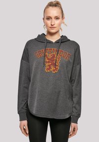 Siva dukserica s kapuljačom koja ima veliki grafički prikaz lava Gryffindora u tamnocrvenoj i žutoj boji, sa vezicom za kapuljaču i opuštenim rukavima.