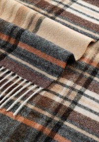 Wolldecke mit einem Karomuster in dunkelgrau, beige, verbranntem Orange und weißen Streifen; weiche Textur mit Fransen. 