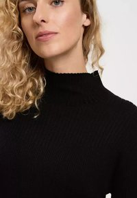 Schwarzer gerippter Pullover mit hohem Kragen, ausgestattet mit einem strukturierten Stoff und einer figurbetonten Passform, die den glatten Halsbereich betont.