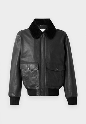 Schwarze Lederbomberjacke mit einem flauschigen schwarzen Kragen, zwei Fronttaschen und gerippten Bündchen und Saum. Glatte Textur, mit Reißverschluss.