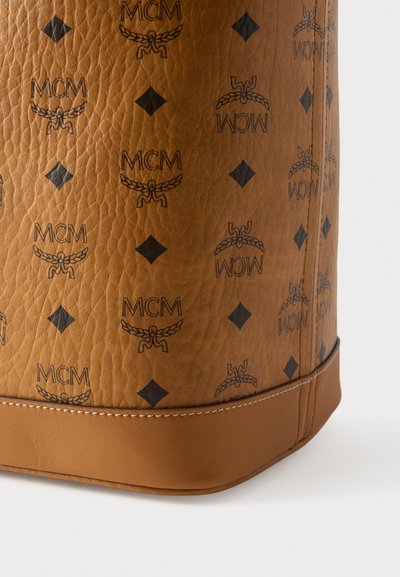 Τσάντα ταμπά δέρματος με ανάγλυφο μαύρο λογότυπο MCM και διαμαντένια σχέδια, με ομαλή υφή και αντίθετη ραμμένη επένδυση στη βάση.