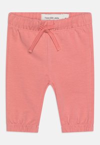 Ružové nohavice z bavlnenej zmesi s elastickým pásom a šnúrou na stiahnutie. Obsahujú zhrnuté manžety a označenie Calvin Klein Jeans na páse.