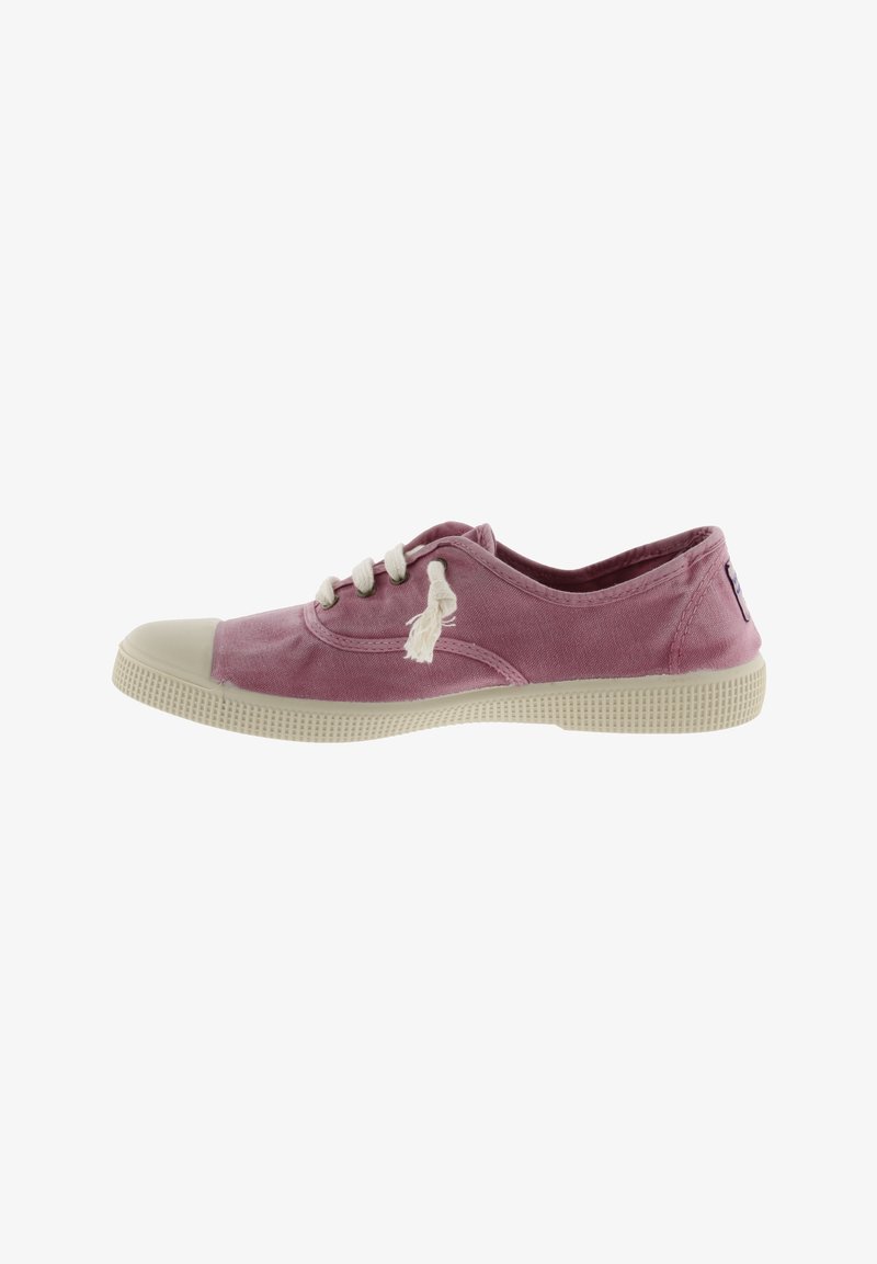 Zapatilla de lona rosa con puntera y suela de goma color crema, presenta cordones blancos y una pequeña etiqueta de acento en el talón. Diseño plano y redondeado.