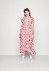 Vestido envolvente floral rosa com mangas em fru-fru e bainha em camadas, apresentando um decote em V, combinado com ténis brancos e meias até ao tornozelo.