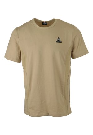T-shirt corto a maniche corte di colore tan, realizzato in cotone con pannelli laterali in rete. Presenta un piccolo logo nero sul lato sinistro del petto e un collo a costine.