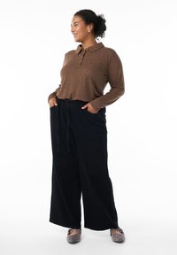 Brown long-sleeve polo shirt with buttoned collar, paired with black wide-leg pants featuring an elastic waistband and side pockets.