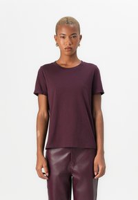 Mauve bavlněné tričko s kulatým výstřihem, krátkými ohrnutými rukávy a uvolněným střihem, v kombinaci s burgundskými kalhotami z umělé kůže.