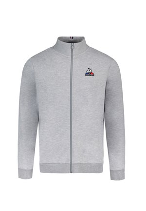 Sudadera gris con cremallera y cuello alto, puños acanalados y cinturilla elástica. Presenta un pequeño logo en el lado izquierdo del pecho. Textura suave.