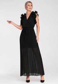Schwarzes Maxikleid mit plisseeartigem Rock, Rüschensleeves, tiefem V-Ausschnitt und tailliertem Bund. Durchscheinender Stoff sorgt für Textur und schichtartige Details.