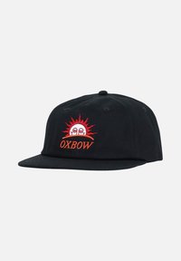 Casquette noire à visière plate, ornée d'un motif de soleil brodé rouge et blanc et du texte « OXBOW » à l'avant. Matériel en coton.