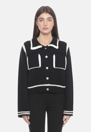 Cardigan corto navy con cuciture bianche a contrasto, grandi tasche frontali e bottoni argentati. Presenta maniche lunghe e tessuto a maglia testurizzato.