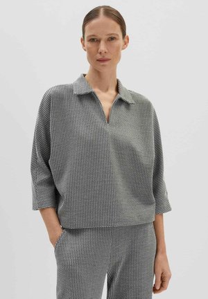Pullover a righe bianco e nero con colletto, maniche a tre quarti, vestibilità morbida e texture soffice. Indossato con pantaloni coordinati.