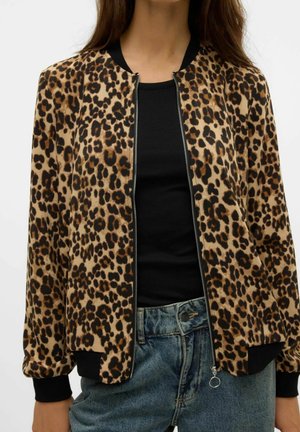 Lederjacke mit Leopardenmuster in Beige und Schwarz, mit einem Reißverschluss auf der Vorderseite, Rippbündchen und einem lässigen Schnitt. Kombiniert mit einem schwarzen Oberteil und Jeans.