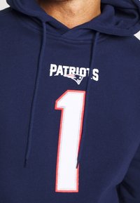 Sudadera en azul marino con el texto "PATRIOTS" y un gran número 1 blanco contorneado en rojo. Tiene capucha con cordón y textura suave.