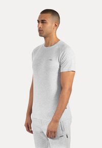 Grå kortærmet t-shirt med rund hals, blød tekstur og et lille logo-patch på brystet. Letvægtsstof for komfort.