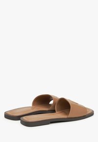 Bruine rubberen sandaal-slippers met open teen, voorzien van een platte zool en een gestructureerde binnenzool voor grip, ontworpen voor eenvoudig aan- en uittrekken.