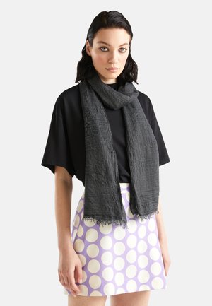 Écharpe grise en tissu léger, drapée autour du cou, avec des bords fringés et un design froissé.