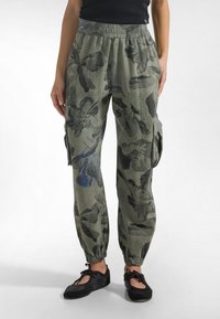 Pantalones cargo en verde oliva con un patrón floral en azul oscuro y negro. Presentan una cintura elástica y puños ajustados en los tobillos.