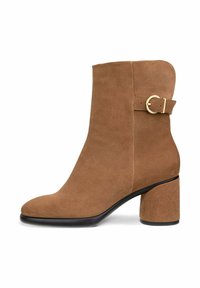 Bottines en suède marron avec un bout arrondi, un accent de boucle dorée et un talon épais. Texture lisse et design minimaliste.