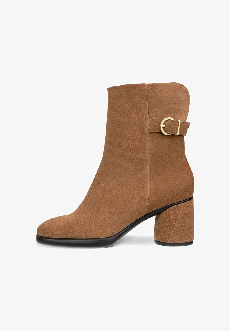 Brune ruskindsankelstøvle med rund tå, en guldtonet spændeaccent og en kraftig hæl. Glat tekstur og minimalistisk design.