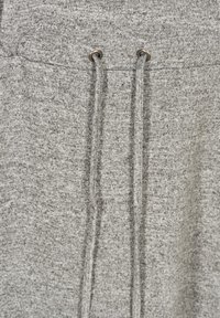 Gros plan sur un tissu gris avec deux cordons de serrage verticaux passés à travers des œillets en métal à la taille.