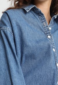 Jeansskjorta i ljusblått, med en knapp-up front, krage och långa ärmar. Materialet har subtil textur och blekning.