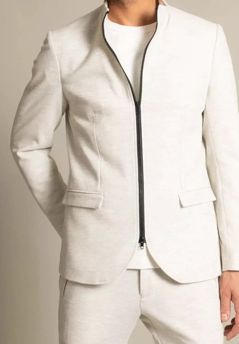 Ljusgrå skräddarsydd jacka med svart dragkedja, två framfickor och en strukturerad krage, tillverkad av ett texturerat tyg.