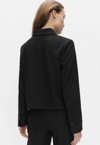 Sort cropped jakke med lange ærmer, notch-krave, en-knaps manchetter og glat stof. Enkel design, strømlinet silhuet, ingen synlige mønstre.