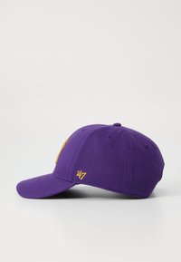 Casquette de baseball violette en tissu avec une visière courbée. Présente une broderie en or avec des lettres et un logo. Sangle ajustable à l'arrière.