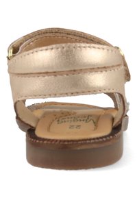 Metallic rose gold sandal with a flat base, two adjustable straps, and a textured insole. Brown rubber sole, subtle stitching details.