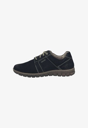 Zapato de ante negro con cordones beige, costuras en contraste y suela acolchada. Presenta una puntera redondeada y un diseño de bajo perfil.