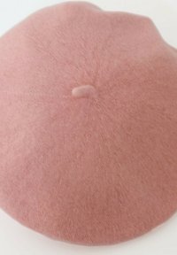 Beret en laine rose avec une texture douce, de forme ronde, et un détail en bouton au centre, présentant une surface lisse et uniforme sans motifs.