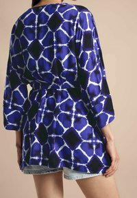Blauwe en zwarte gewatteerde robe met driekwartmouwen, vastgebonden in de taille, met een gedurfde geometrische print op een zijdezachte stof.
