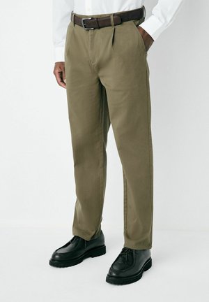 Olive green trousers with a straight-cut design, featuring belt loops and a brown leather belt. Paired with black lace-up shoes.