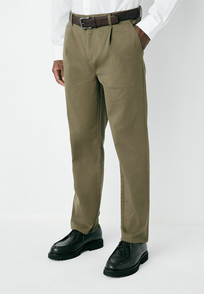 Olive green trousers with a straight-cut design, featuring belt loops and a brown leather belt. Paired with black lace-up shoes.