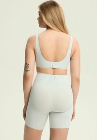 Jasnoniebieski zestaw bielizny, wykonany z gładkiego, elastycznego materiału. Biustonosz ma niskie plecy i regulowane ramiączka; szorty są dopasowane i ozdobione przeszyciami.