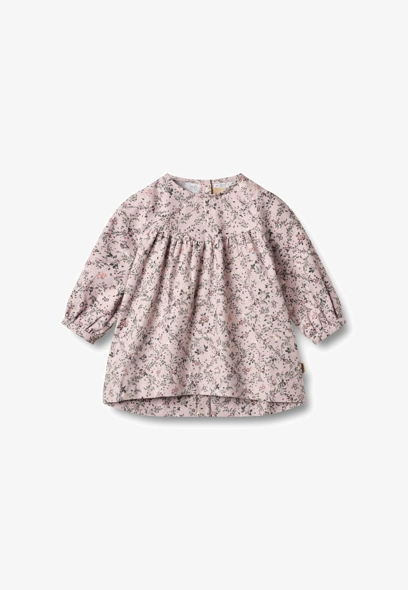 Blouse longue à manches longues rose clair avec une taille froncée, ornée d'un motif floral en vert et rouge, décolletée arrondie et fermée par un bouton au dos.