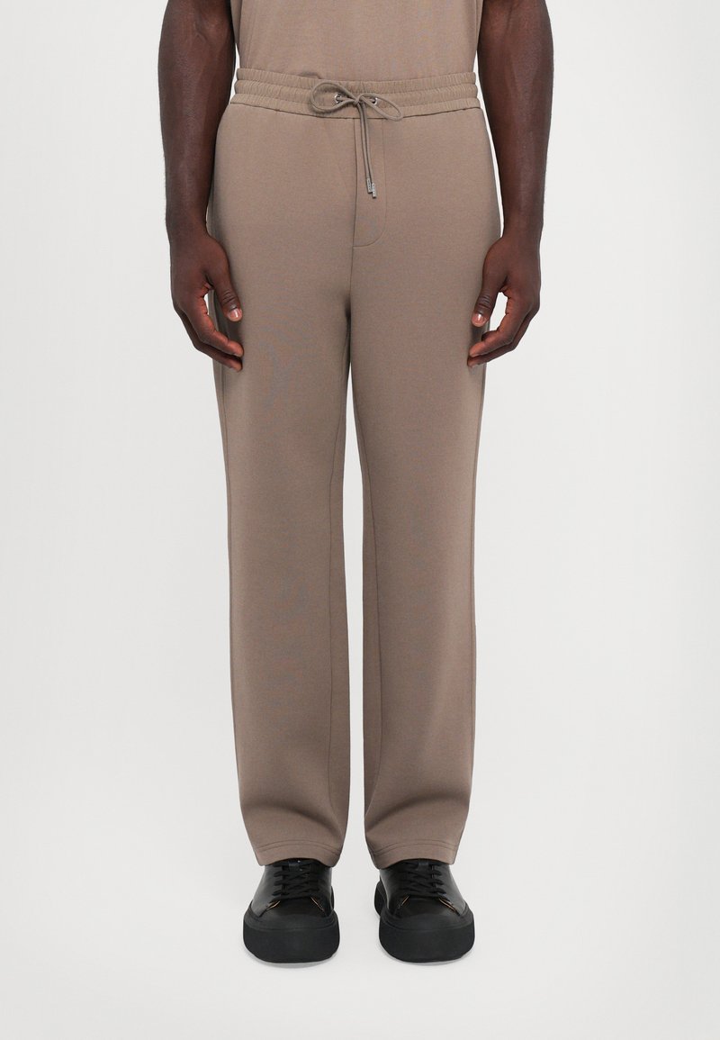 Beige joggebukser med elastisk midje og justerbar snor, har en avslappet passform og rett ben-design.