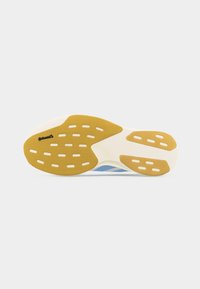 Semelle d'une chaussure de course avec des zones de grip en caoutchouc jaune et une semelle intermédiaire blanche, affichant le logo de la marque Continental près de la section des orteils.