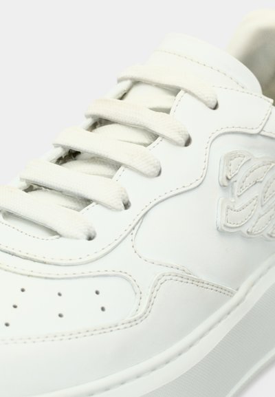 Άσπρο δερμάτινο αθλητικό παπούτσι με υφασμένη λεπτομέρεια στο πλάι, λευκά επίπεδα κορδόνια, μικρές τρύπες στο μπροστινό μέρος και μια απλή, λιτή σχεδίαση.