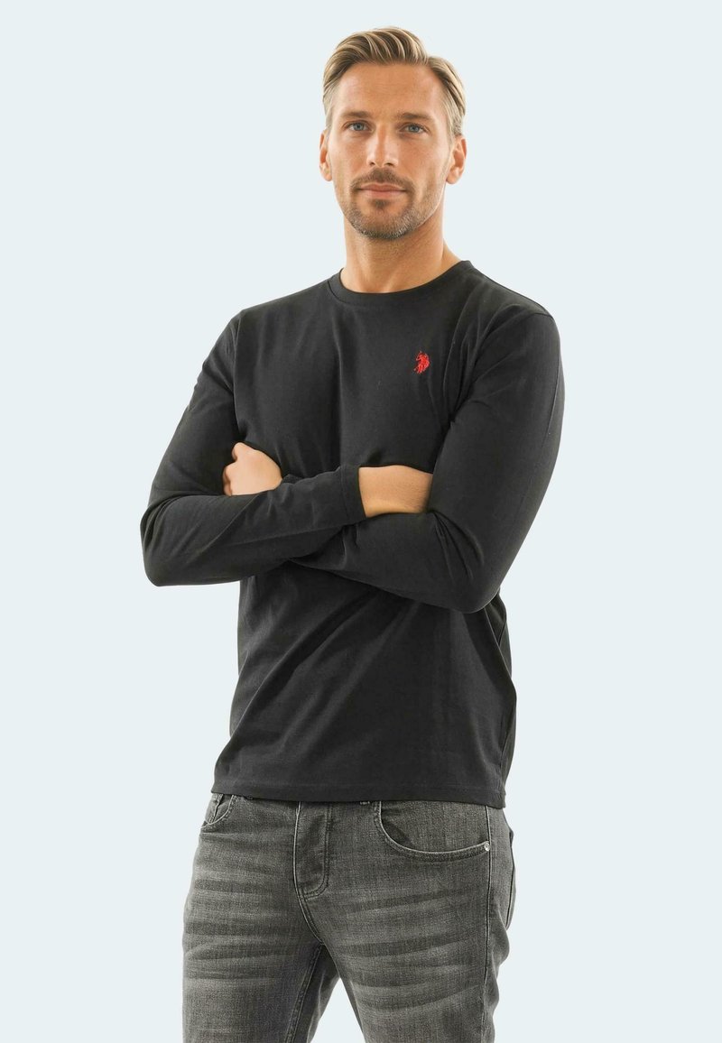 Long-sleeve black t-shirt made of cotton, featuring a small red logo on the chest. The shirt has a round neckline and fitted sleeves.